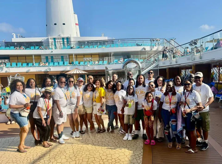 A travel group gathered for a photograph beside a cruise ship