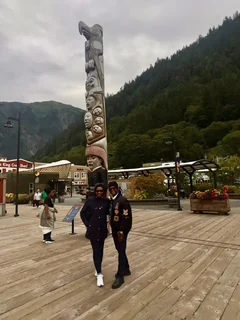 Two travelers standing near a carved monument in a mountain plaza