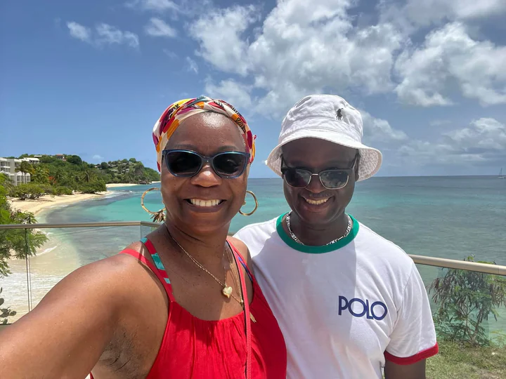 John and Veronica smiling together beside a tropical beach