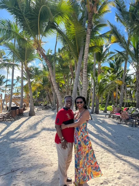 John and Veronica posing together on a palm-lined beach