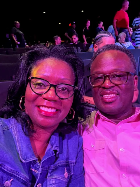 John and Veronica sharing an evening selfie under colorful lights